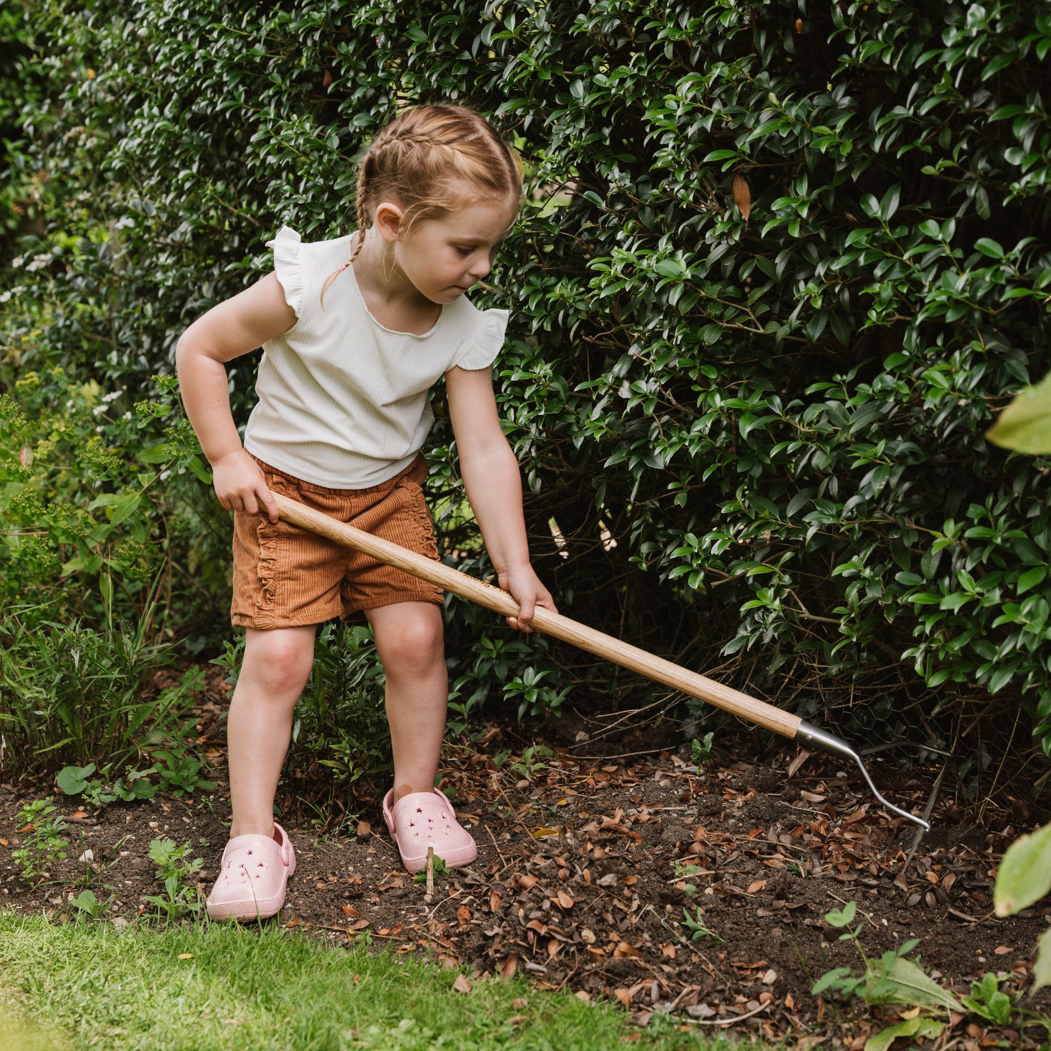 child raking in garden border