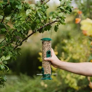All Weather seed feeder being placed in tree with seed