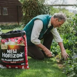Man planting in garden border with new horizon compost
