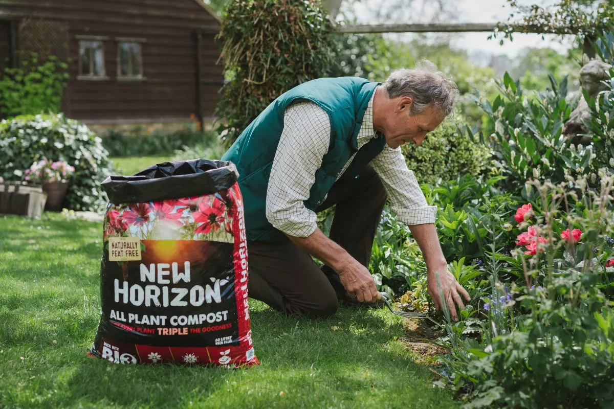 Man planting in garden border with new horizon compost